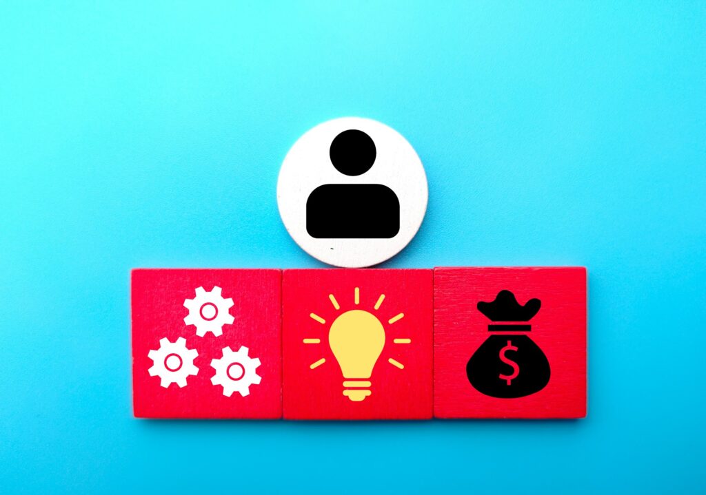 Close-up shot of a round user icon over the wooden cubes with icons of management, ideas, and money