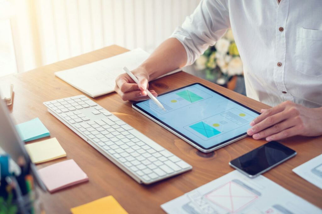 Designer man drawing a website outline and website ux app development on mobile phone.
