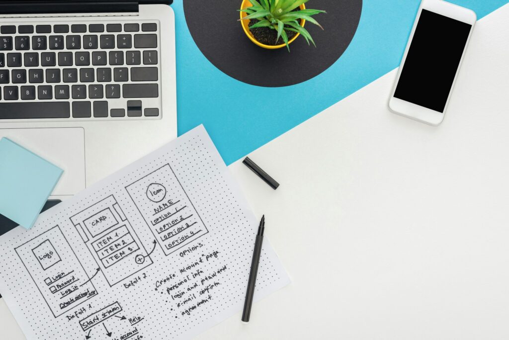 top view of website design template and felt-tip pen near laptop, smartphone, plant on abstract