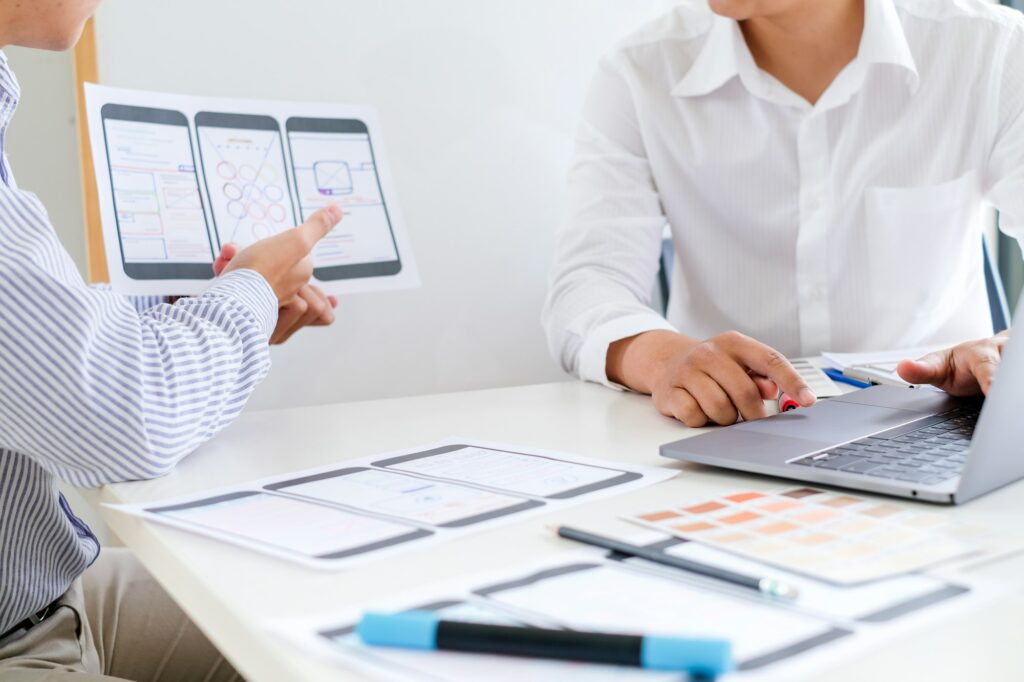 Two Asian men are working together to design websites and application on mobile phone.
