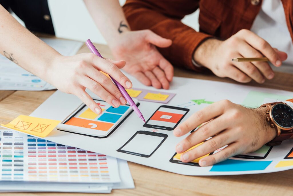 Cropped view of designers planning user experience design of mobile website with frameworks on table